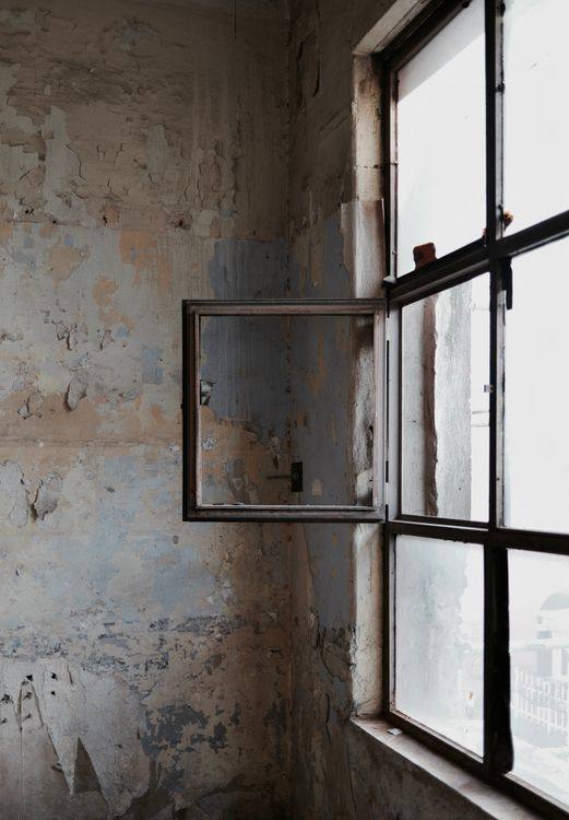 Black metal window frame set in a weathered light-coloured wall