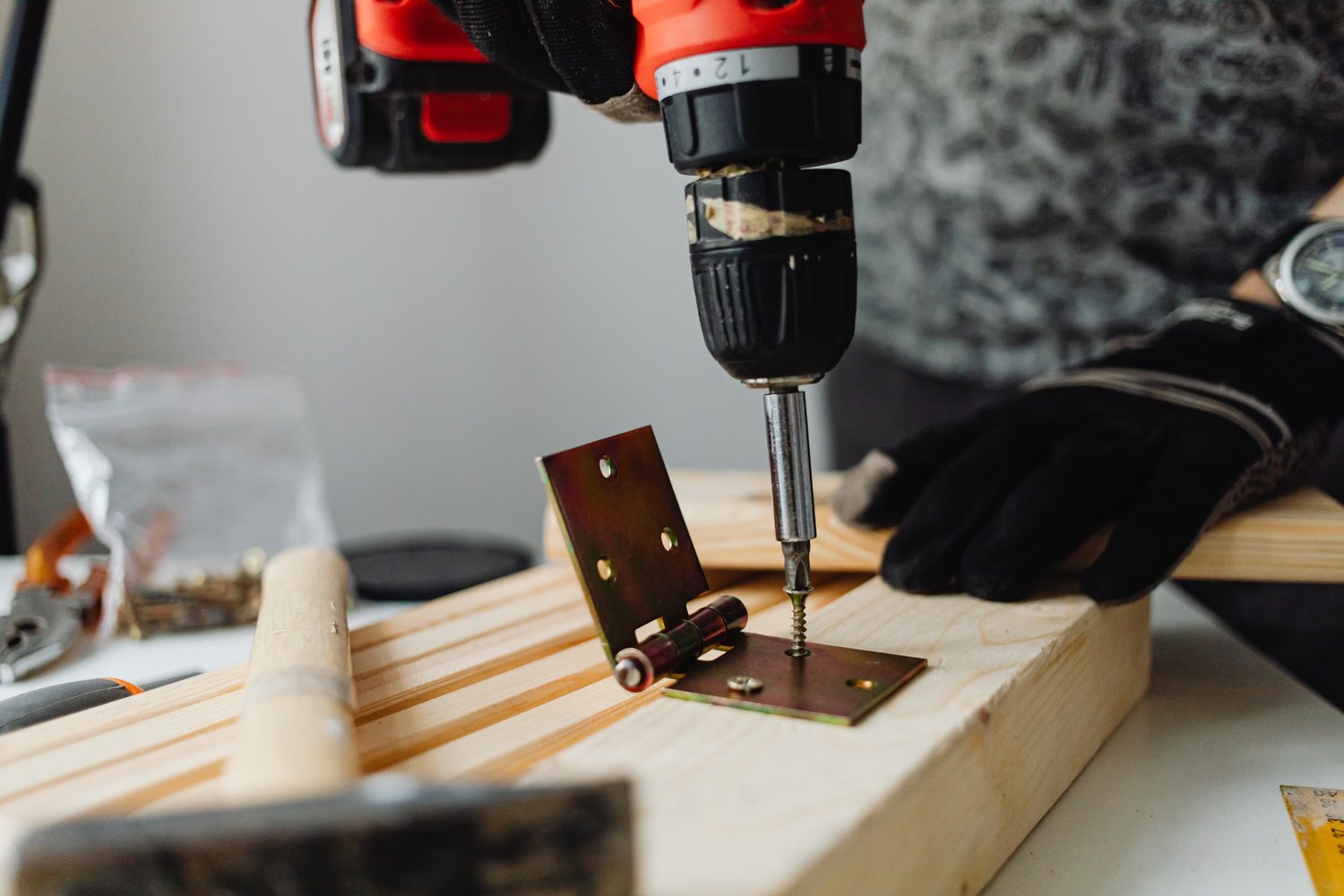Power drill being used to fit a metal hinge into wood