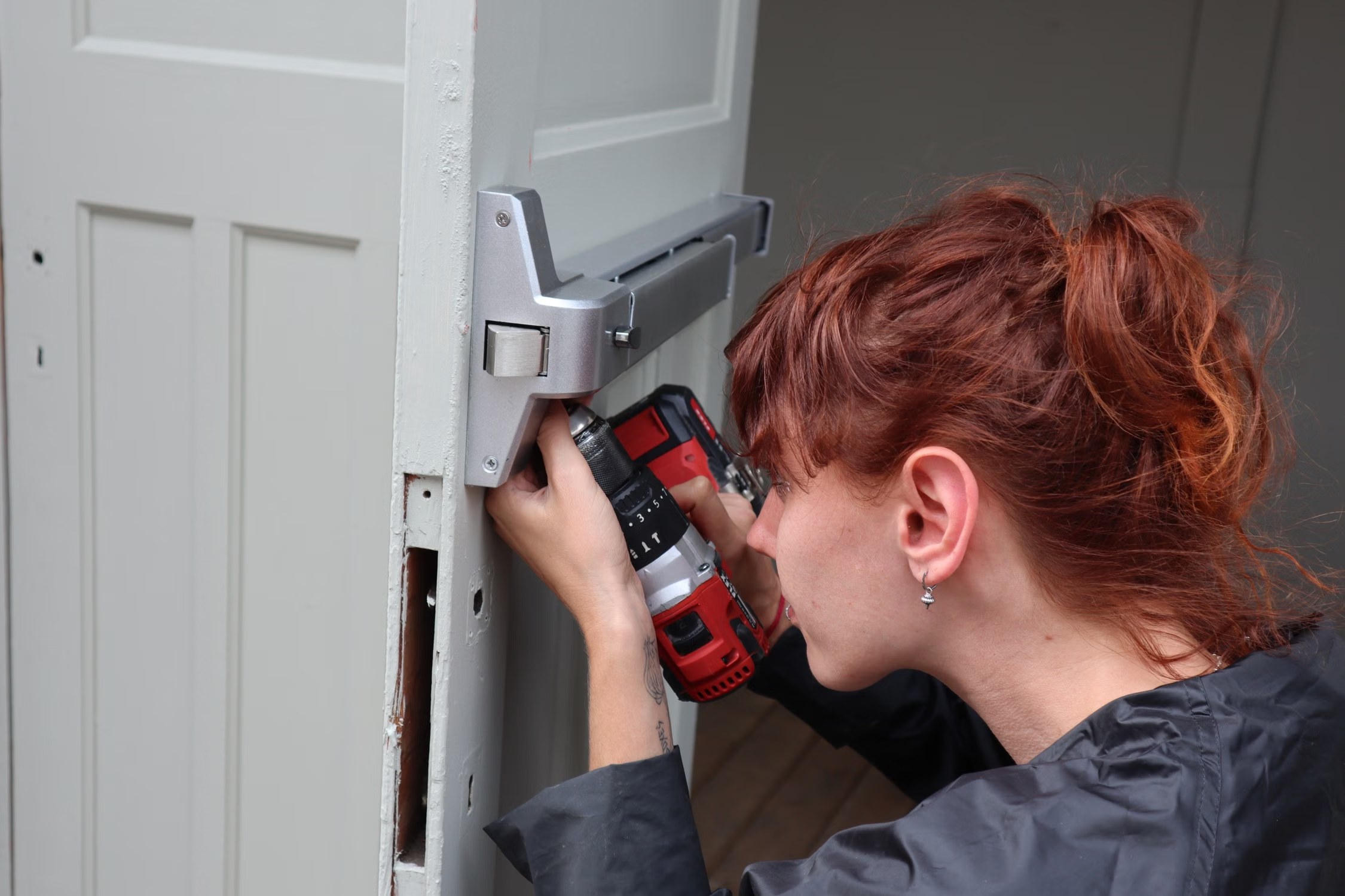 Installer using a drill while fitting a door