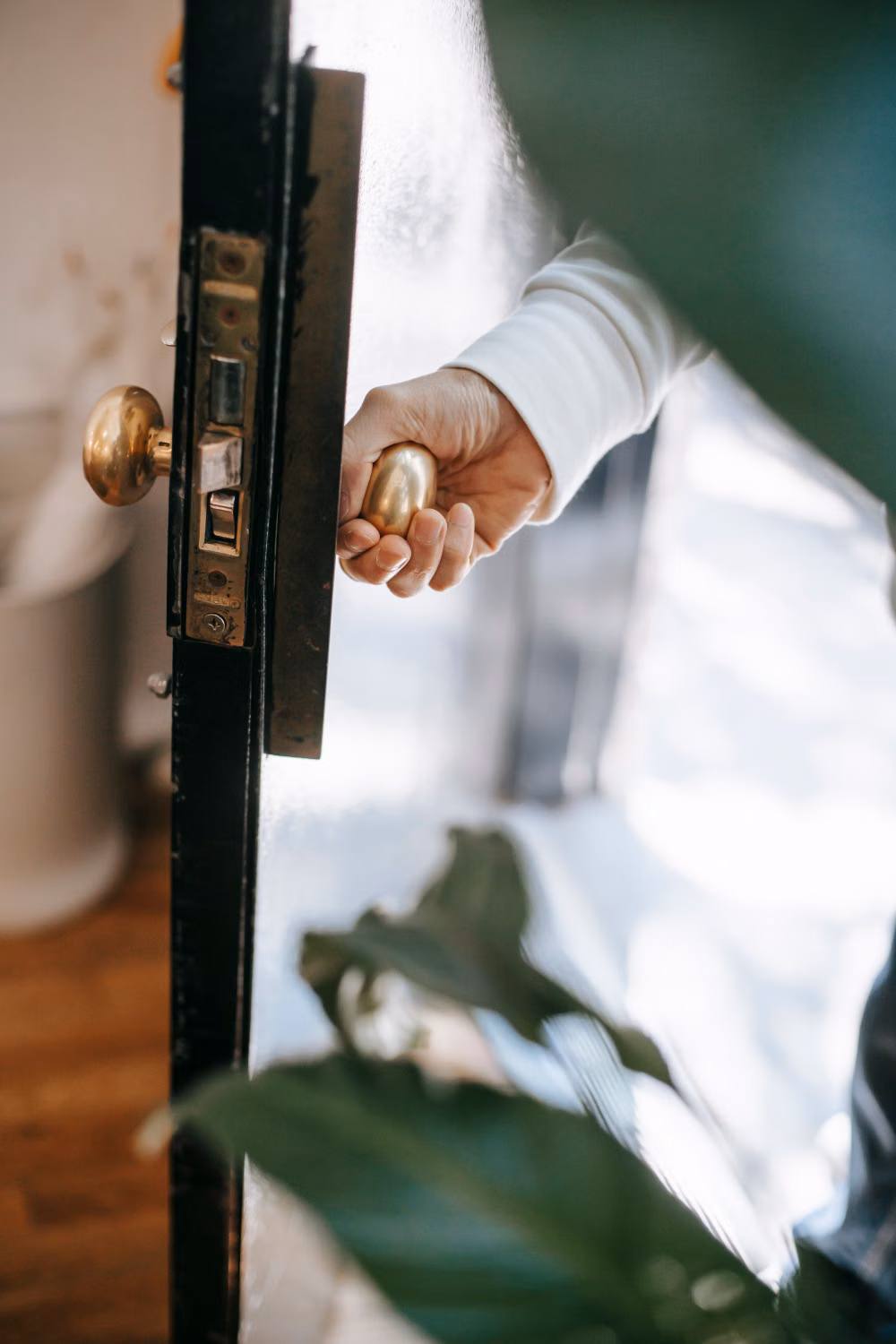 Hand opening a residential door by its metal handle