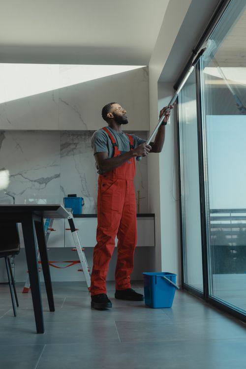 Cleaner maintaining a large window in a modern home