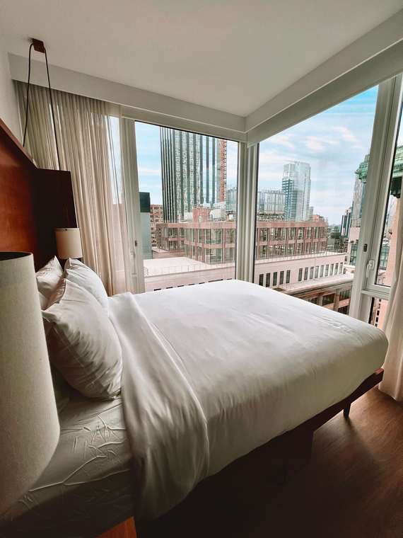 Contemporary hotel bedroom beside floor-to-ceiling city windows