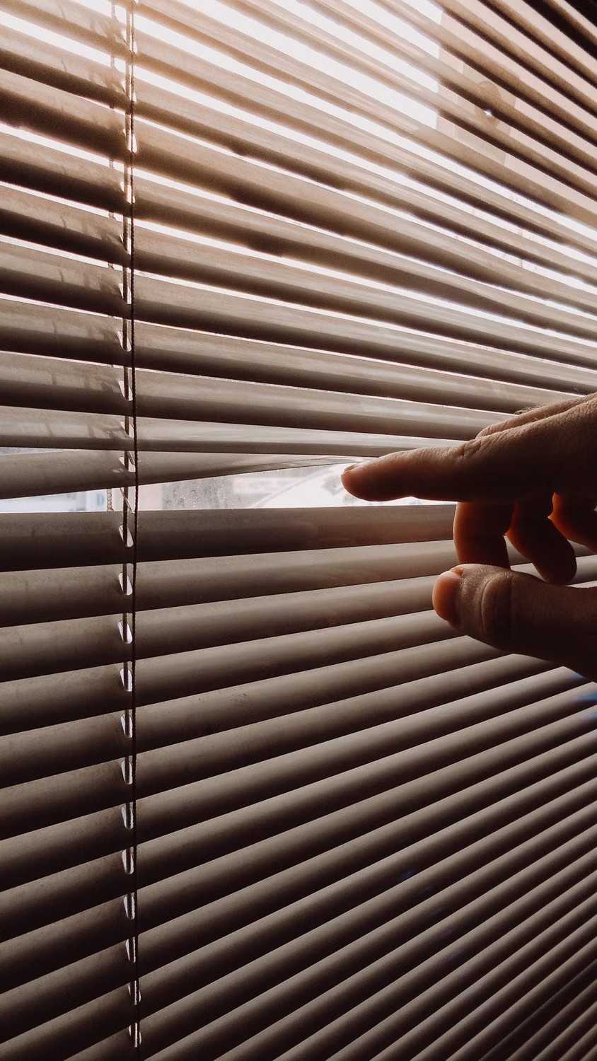 Hand carefully checking the movement of adjustable window slats