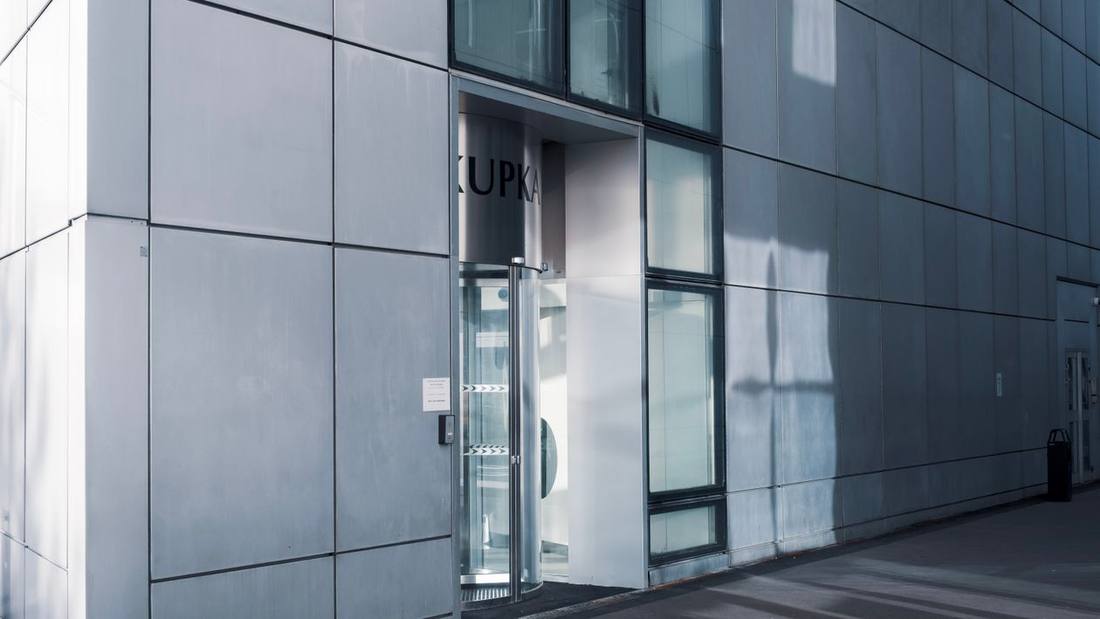 Modern commercial glass entrance beneath a reflective façade