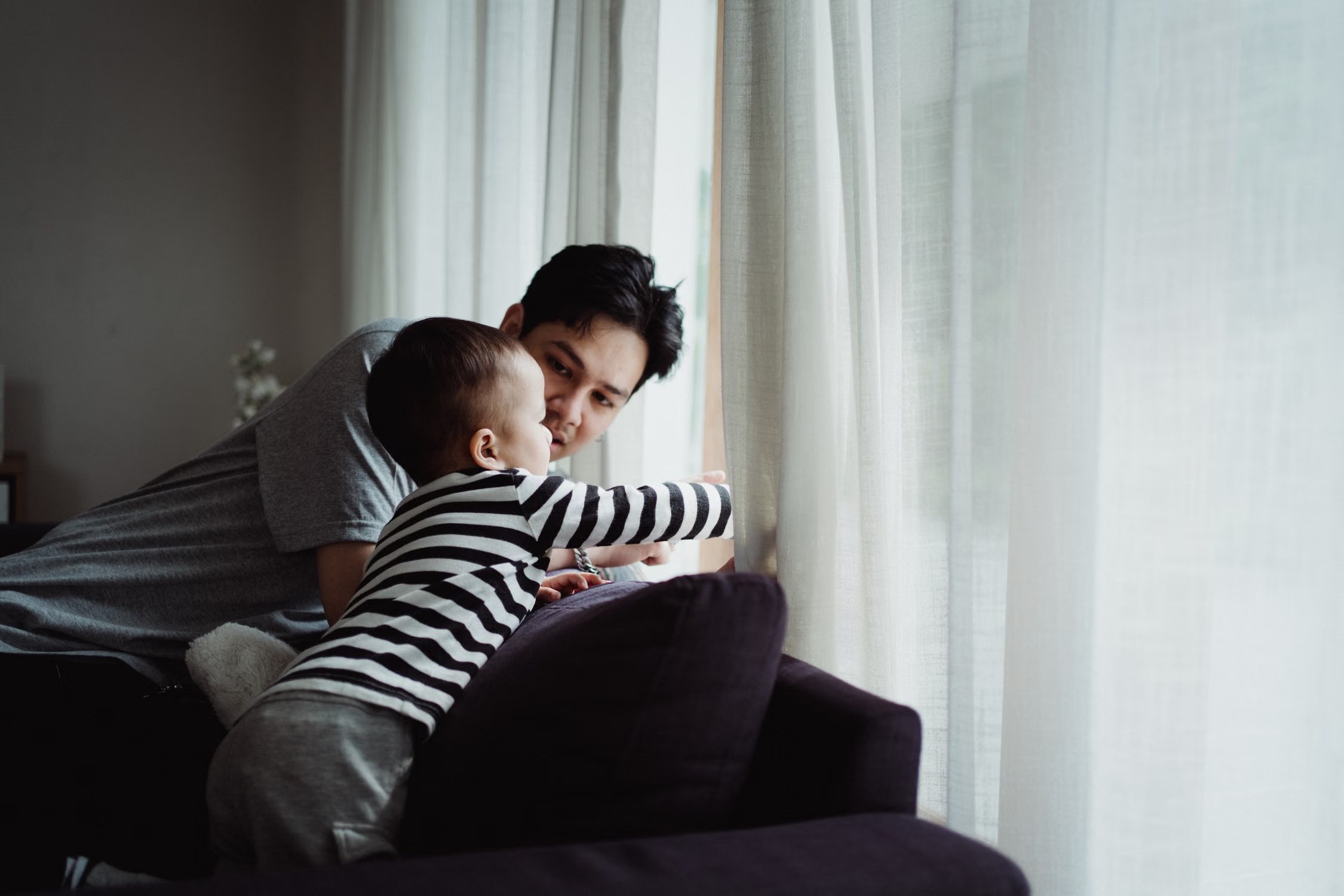 Father and son looking through a window from inside a home