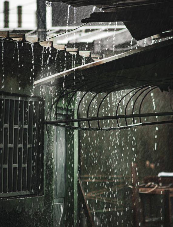 Heavy rain pouring from a city roof edge