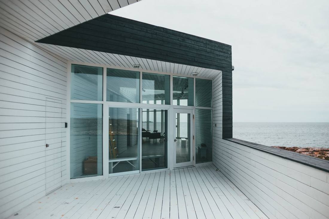 House with broad glazed doors facing an exposed coastal view