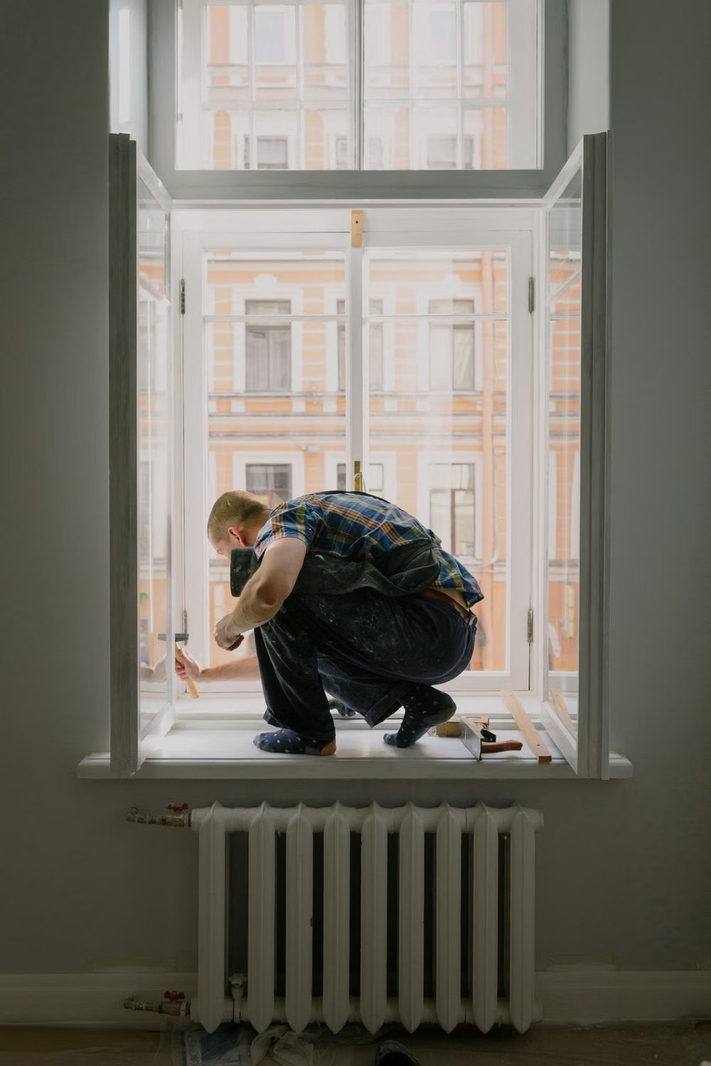 Window repair technician working safely beside an open window