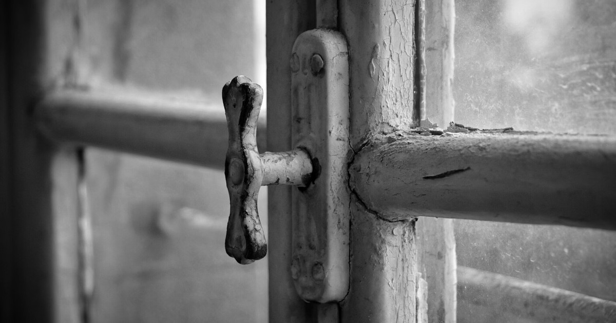 Close-up of an older window handle showing worn hardware
