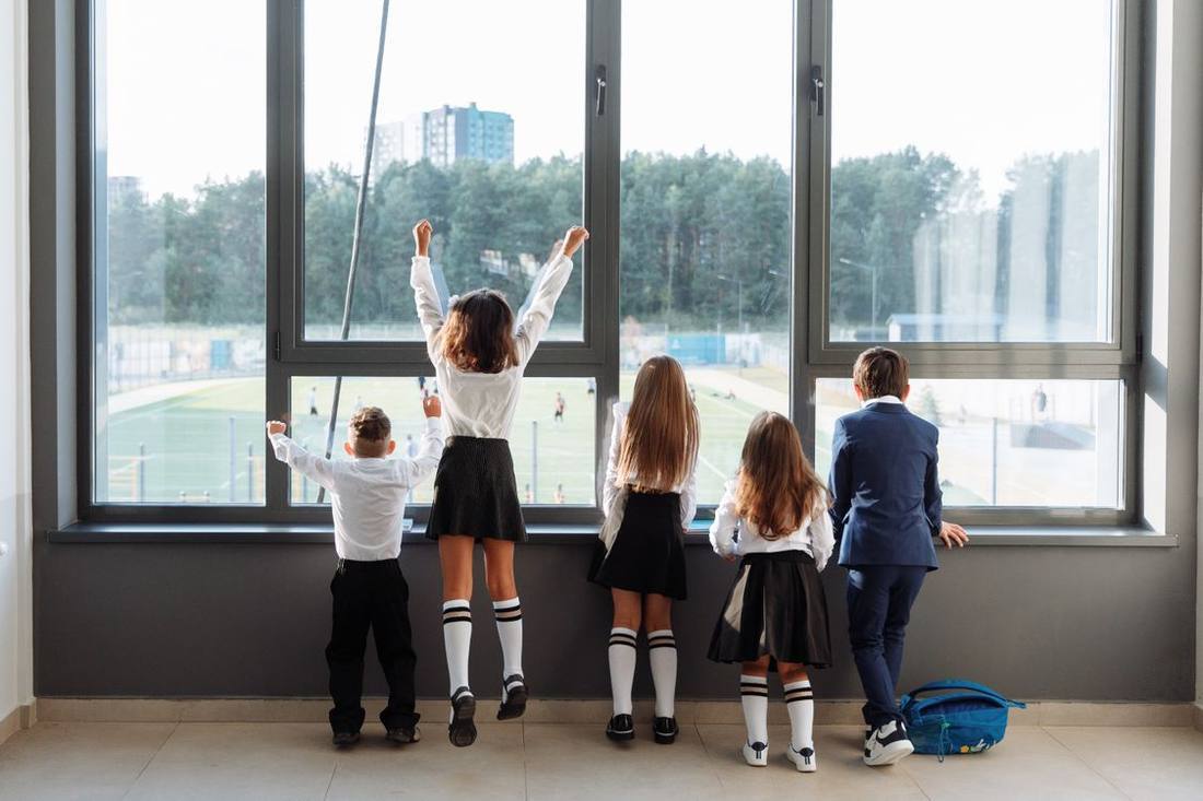 Schoolchildren looking outside through a large classroom window