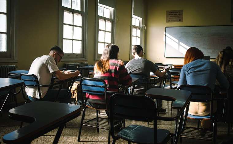 Students taking an exam in a classroom lit by windows