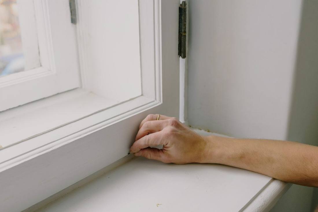 Person touching the inner edge of a residential window frame