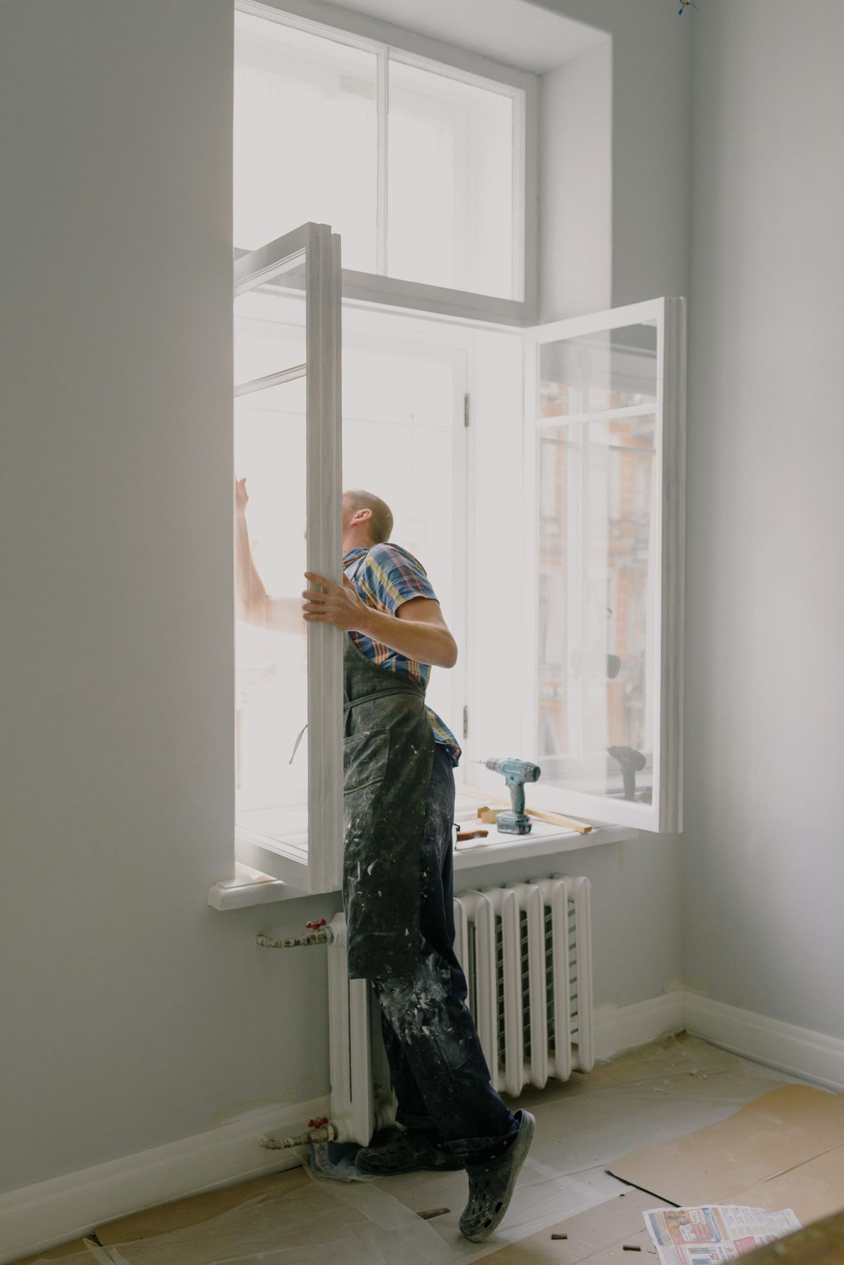Window installer positioning a glazed frame during renovation