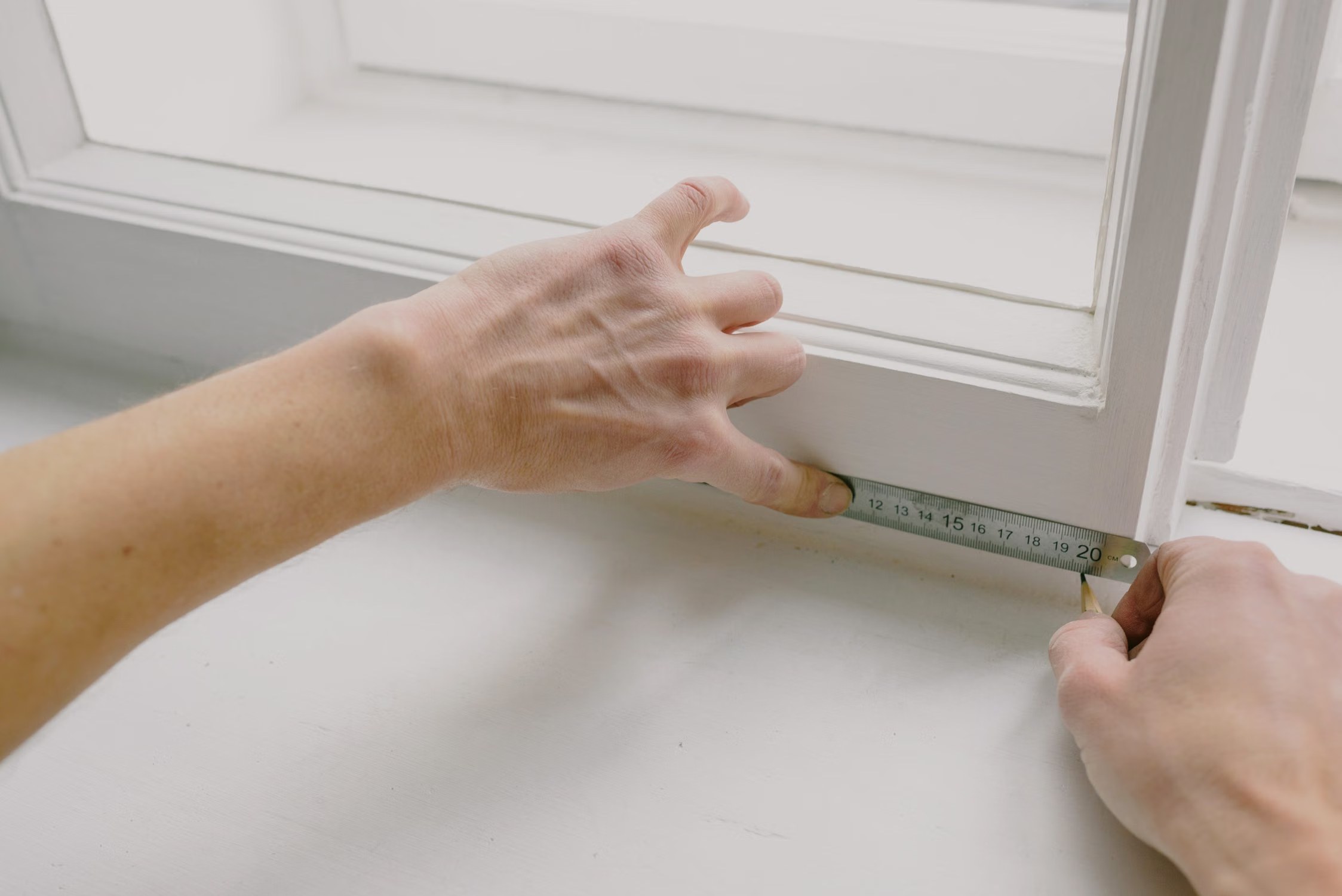 Worker measuring a window frame with a metal ruler