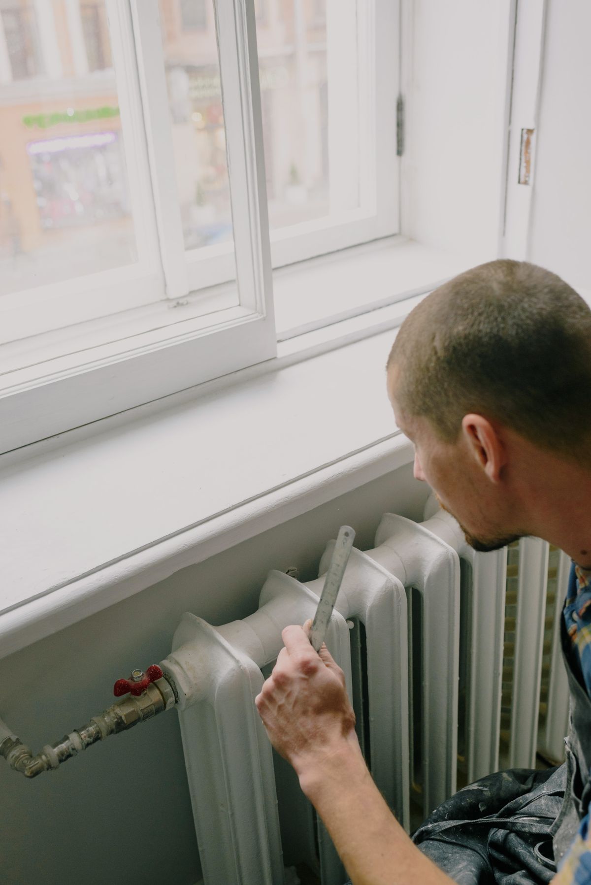 Tradesperson measuring below an open window during renovation