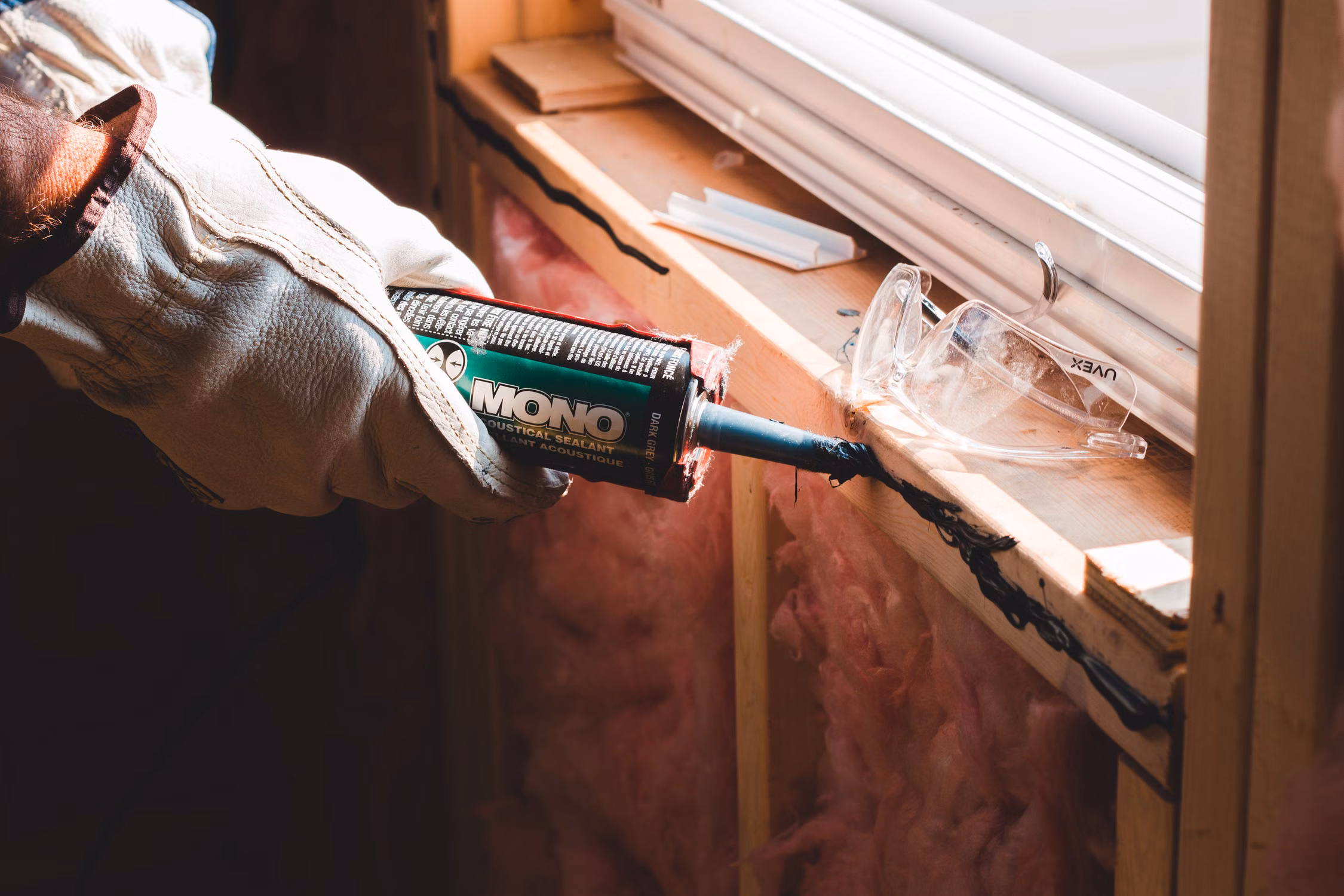 Worker applying sealant along a window frame joint