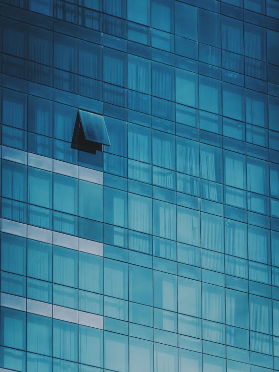 Blue glass building façade with one open window