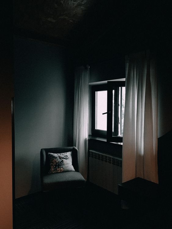 Armchair in a dim corner beside a window and curtains