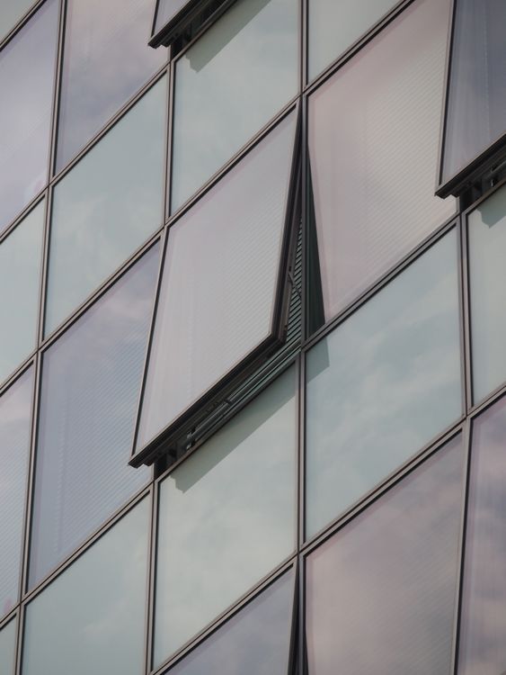 Modern glass building façade with several open windows