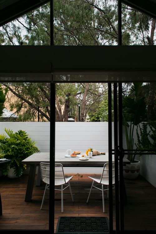 Open glass doors leading to a planted outdoor terrace