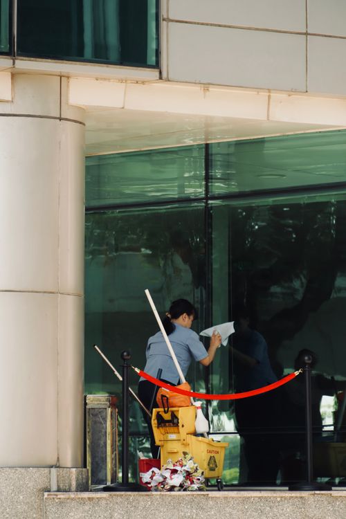 Worker cleaning a large glazed window with cleaning equipment