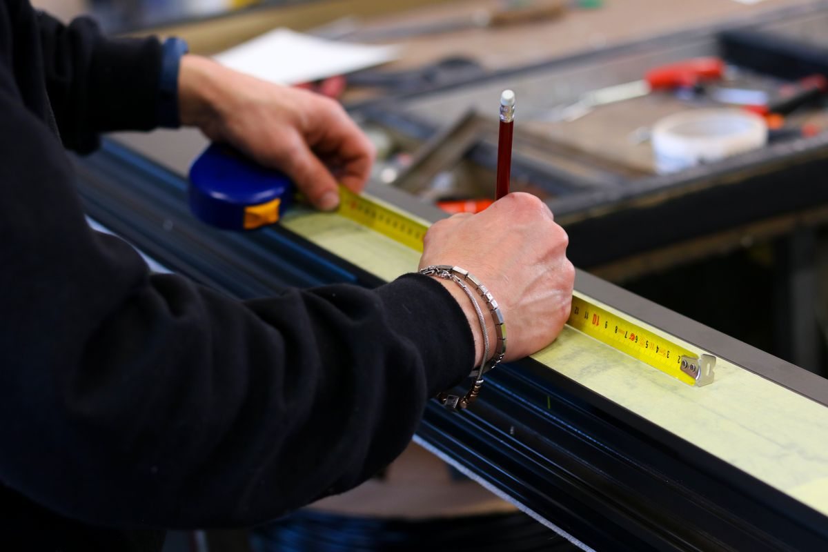 Worker measuring an aluminium frame in a workshop