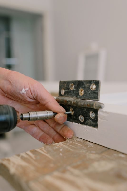 Installer fastening a metal window hinge