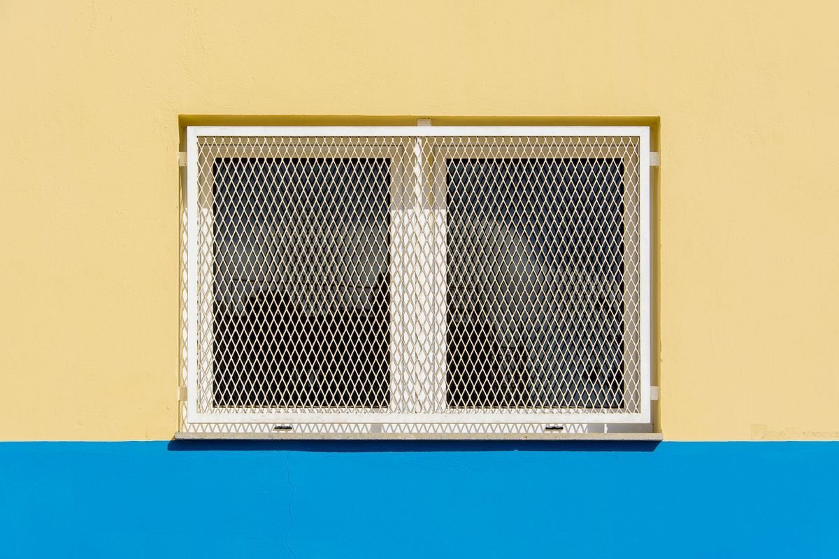 Barred window on a yellow building facade