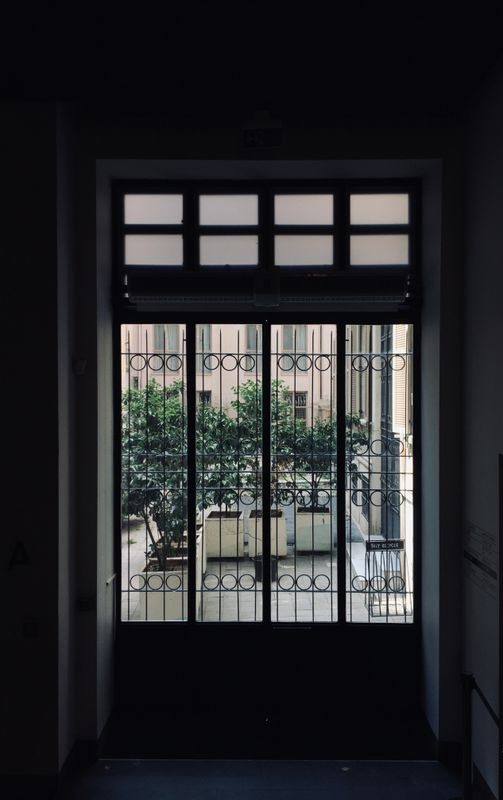 Black metal-framed glass opening toward a courtyard