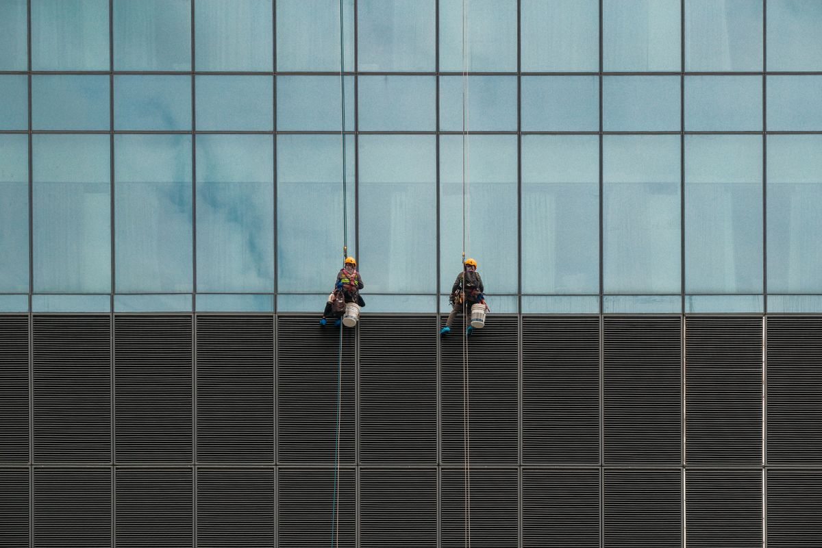 Professional cleaners working from ropes on a facade