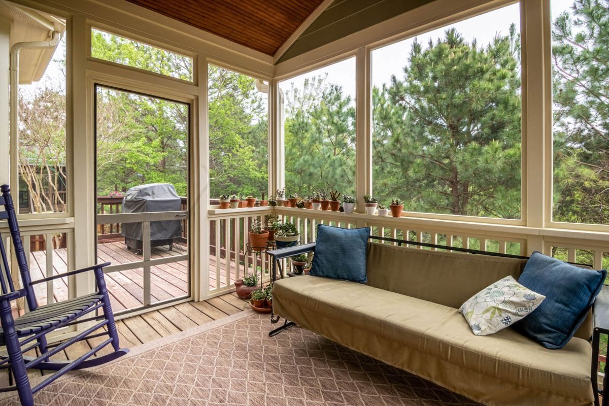 Screened porch with furniture and surrounding trees