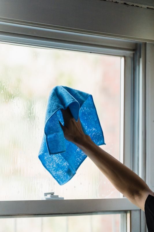 Hand cleaning glass with a blue cloth