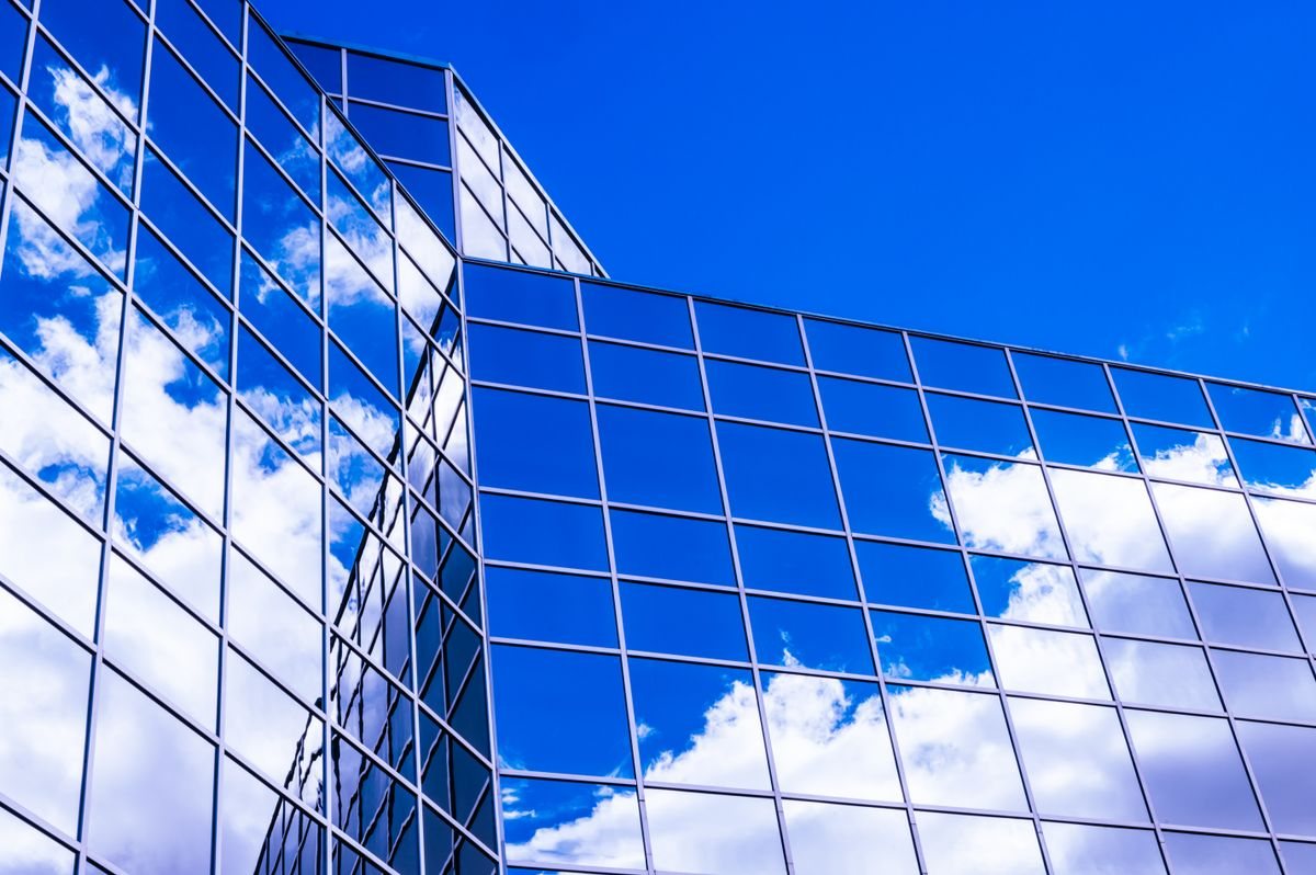 Blue glass building reflecting clouds and sky