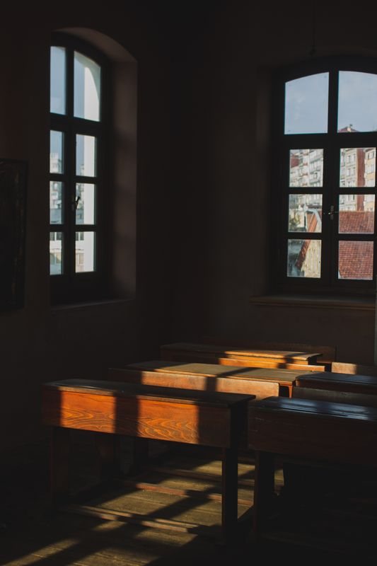 Classroom desks arranged beside large windows