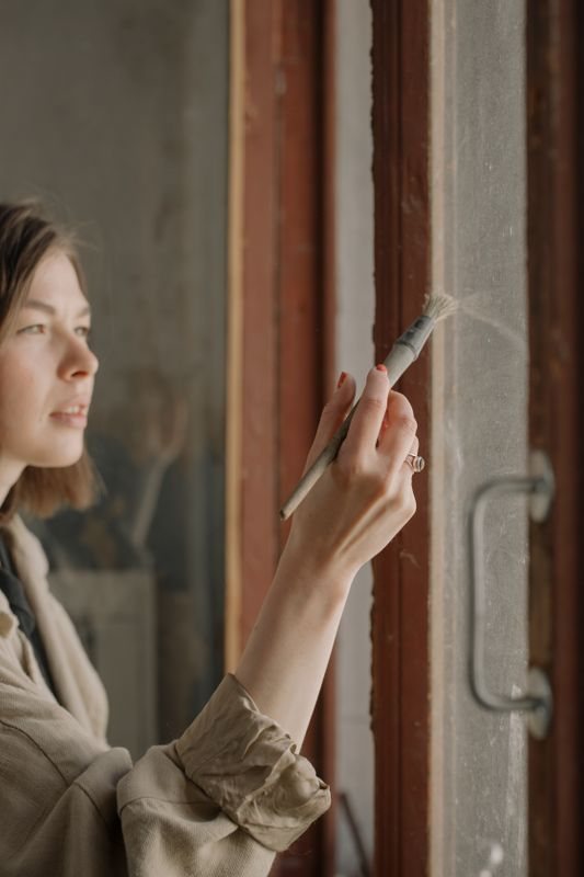 Person painting a timber window frame indoors