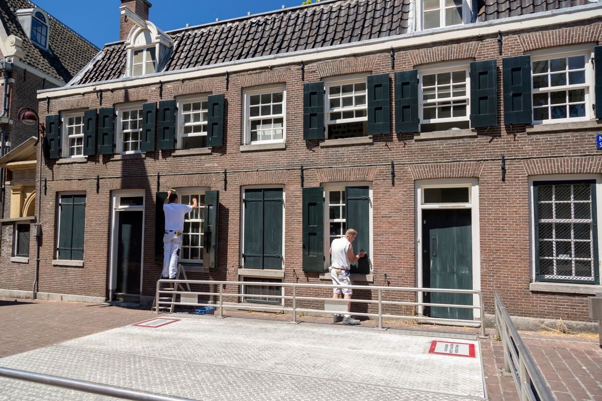 Painters refurbishing a brick house around its windows