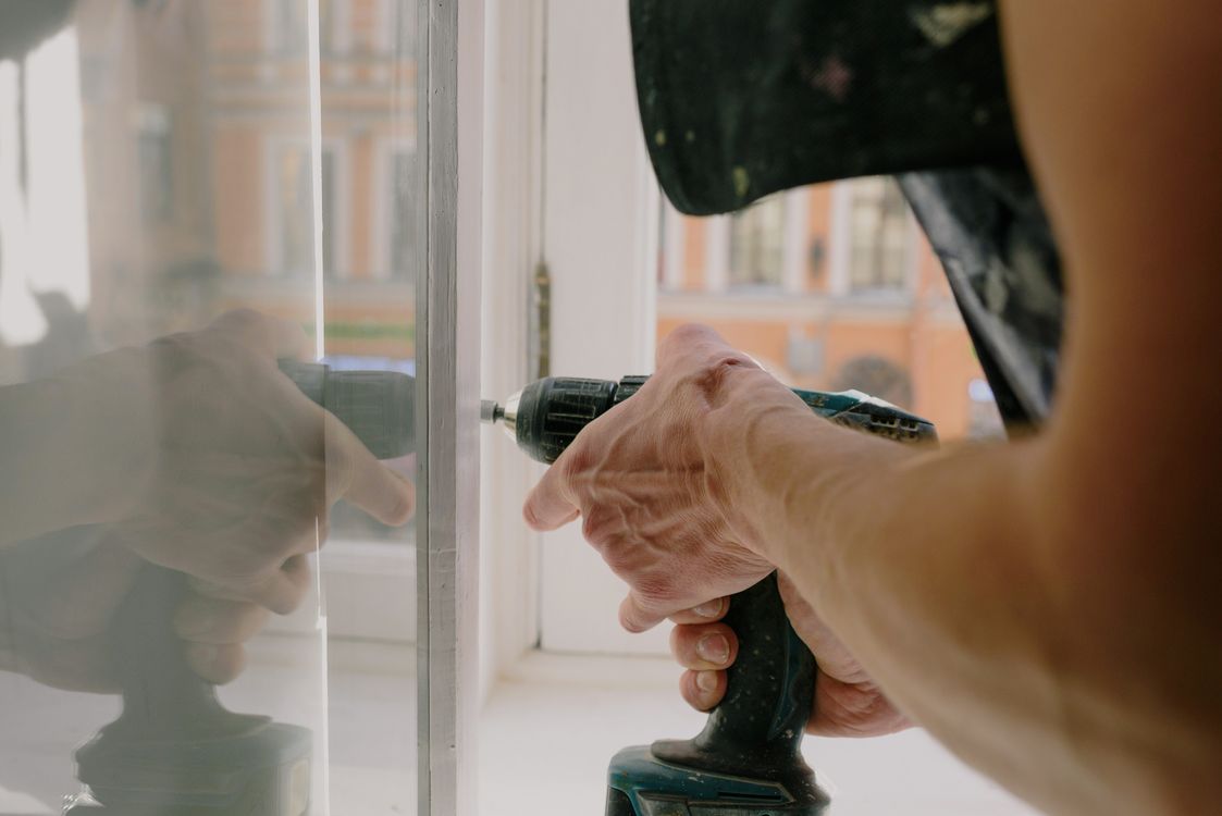 Worker using a cordless screwdriver on a white window frame