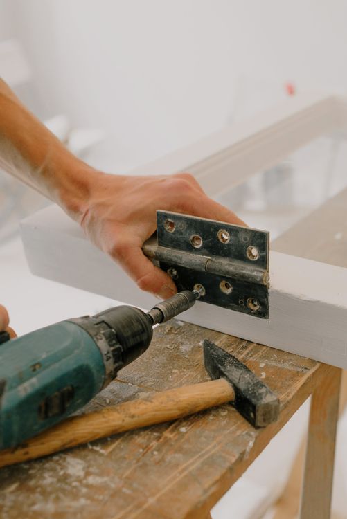 Craftsperson fastening a metal hinge to a window frame